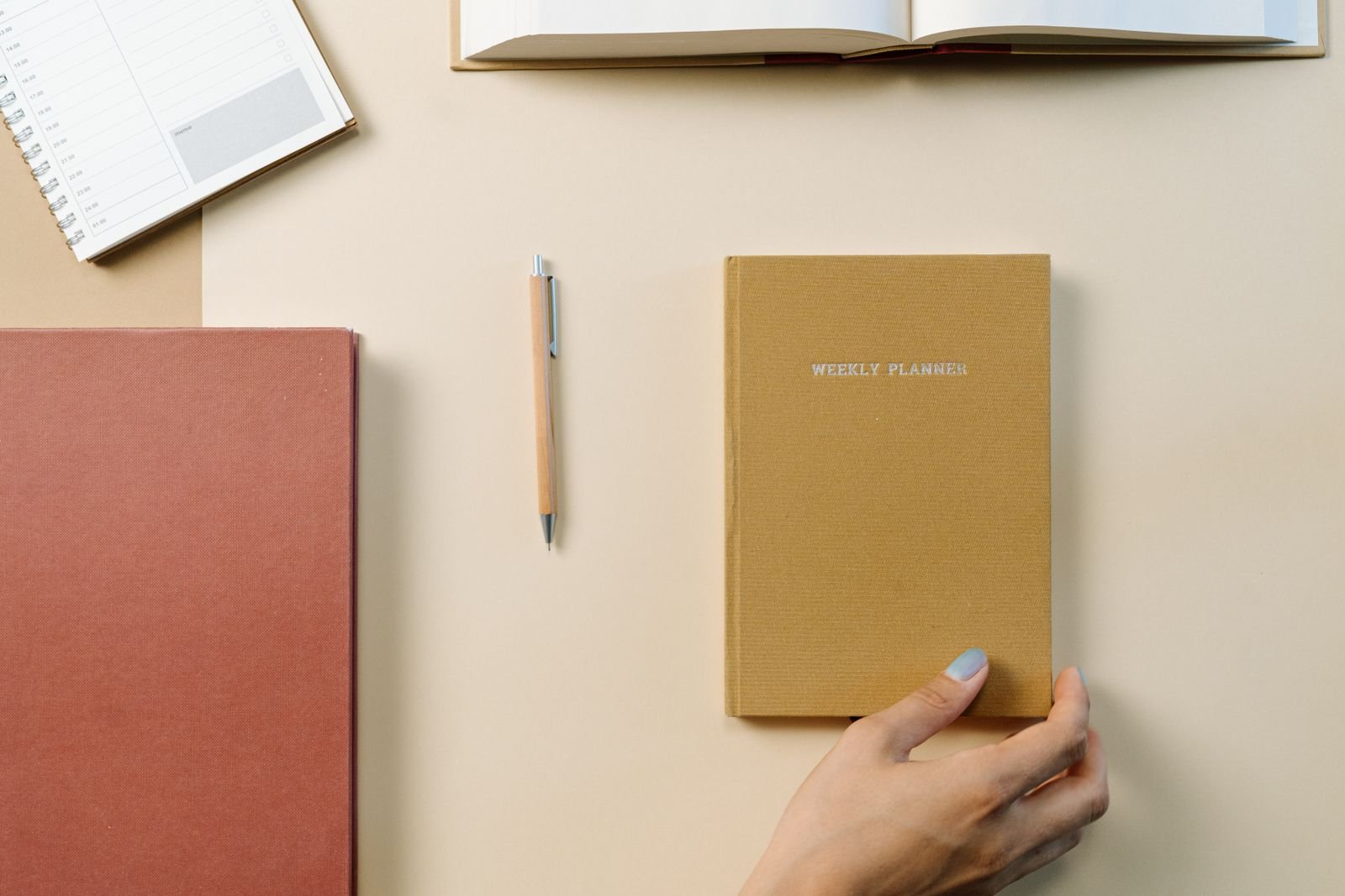 A weekly planner and notebooks arranged on a desk